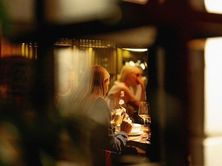 Diners at a candlelit restaurant table seen through shelving