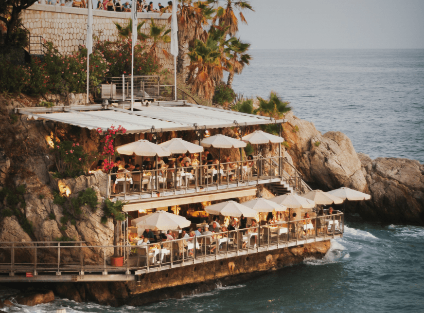 Cafe on cliff over looking sea with white umbrellas